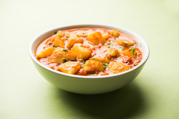 Indian food - Aloo curry masala. Potato cooked with spices and herbs in a tomato curry. served in a bowl over moody background. selective focus