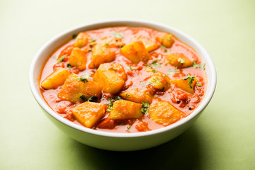 Indian food - Aloo curry masala. Potato cooked with spices and herbs in a tomato curry. served in a bowl over moody background. selective focus