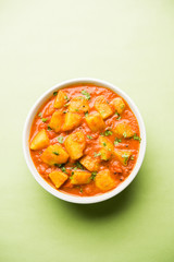 Indian food - Aloo curry masala. Potato cooked with spices and herbs in a tomato curry. served in a bowl over moody background. selective focus