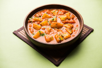 Indian food - Aloo curry masala. Potato cooked with spices and herbs in a tomato curry. served in a bowl over moody background. selective focus