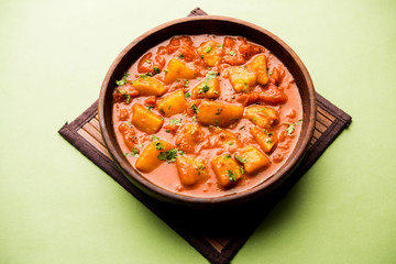 Indian food - Aloo curry masala. Potato cooked with spices and herbs in a tomato curry. served in a bowl over moody background. selective focus