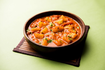 Indian food - Aloo curry masala. Potato cooked with spices and herbs in a tomato curry. served in a bowl over moody background. selective focus