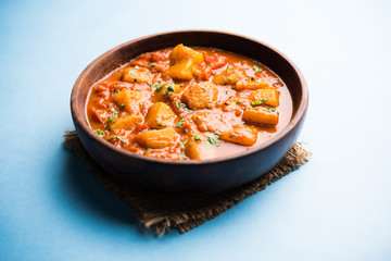 Indian food - Aloo curry masala. Potato cooked with spices and herbs in a tomato curry. served in a bowl over moody background. selective focus