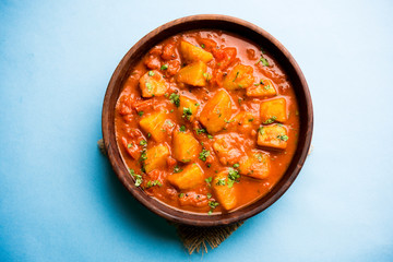 Indian food - Aloo curry masala. Potato cooked with spices and herbs in a tomato curry. served in a bowl over moody background. selective focus