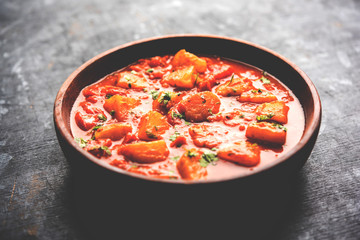 Indian food - Aloo curry masala. Potato cooked with spices and herbs in a tomato curry. served in a bowl over moody background. selective focus