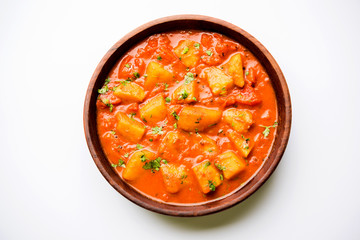 Indian food - Aloo curry masala. Potato cooked with spices and herbs in a tomato curry. served in a bowl over moody background. selective focus