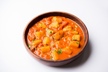 Indian food - Aloo curry masala. Potato cooked with spices and herbs in a tomato curry. served in a bowl over moody background. selective focus