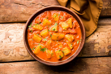 Indian food - Aloo curry masala. Potato cooked with spices and herbs in a tomato curry. served in a bowl over moody background. selective focus