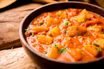 Indian food - Aloo curry masala. Potato cooked with spices and herbs in a tomato curry. served in a bowl over moody background. selective focus