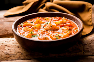 Indian food - Aloo curry masala. Potato cooked with spices and herbs in a tomato curry. served in a bowl over moody background. selective focus