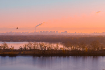 Beautiful view at city over the river at early autumn morning sunrise. Kiev, Ukraine, view to left bank. Urban air pollution concept. World environment day.