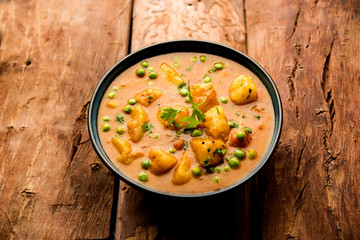 Indian Aloo Mutter curry - Potato and Peas immersed in an Onion Tomato Gravy and garnished with coriander leaves. Served in a Karahi/kadhai or pan or bowl. selective focus