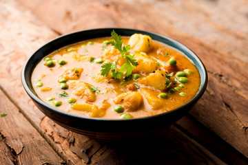 Indian Aloo Mutter curry - Potato and Peas immersed in an Onion Tomato Gravy and garnished with coriander leaves. Served in a Karahi/kadhai or pan or bowl. selective focus