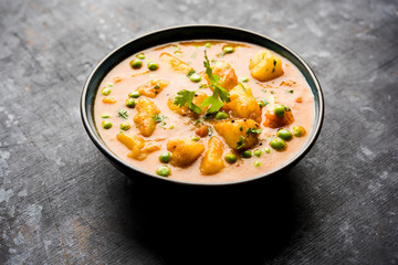 Indian Aloo Mutter curry - Potato and Peas immersed in an Onion Tomato Gravy and garnished with coriander leaves. Served in a Karahi/kadhai or pan or bowl. selective focus