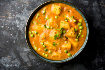 Indian Aloo Mutter curry - Potato and Peas immersed in an Onion Tomato Gravy and garnished with coriander leaves. Served in a Karahi/kadhai or pan or bowl. selective focus - obrazy, fototapety, plakaty