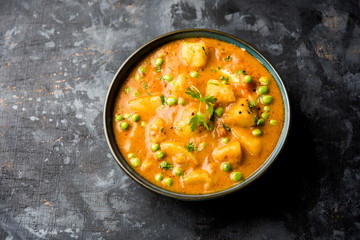 Indian Aloo Mutter curry - Potato and Peas immersed in an Onion Tomato Gravy and garnished with coriander leaves. Served in a Karahi/kadhai or pan or bowl. selective focus