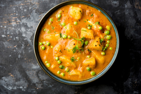 Indian Aloo Mutter curry - Potato and Peas immersed in an Onion Tomato Gravy and garnished with coriander leaves. Served in a Karahi/kadhai or pan or bowl. selective focus