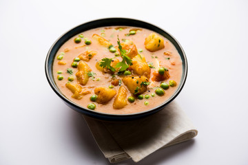 Indian Aloo Mutter curry - Potato and Peas immersed in an Onion Tomato Gravy and garnished with coriander leaves. Served in a Karahi/kadhai or pan or bowl. selective focus