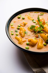 Indian Aloo Mutter curry - Potato and Peas immersed in an Onion Tomato Gravy and garnished with coriander leaves. Served in a Karahi/kadhai or pan or bowl. selective focus