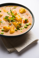 Indian Aloo Mutter curry - Potato and Peas immersed in an Onion Tomato Gravy and garnished with coriander leaves. Served in a Karahi/kadhai or pan or bowl. selective focus