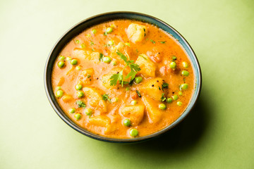 Indian Aloo Mutter curry - Potato and Peas immersed in an Onion Tomato Gravy and garnished with coriander leaves. Served in a Karahi/kadhai or pan or bowl. selective focus