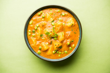 Indian Aloo Mutter curry - Potato and Peas immersed in an Onion Tomato Gravy and garnished with coriander leaves. Served in a Karahi/kadhai or pan or bowl. selective focus