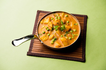 Indian Aloo Mutter curry - Potato and Peas immersed in an Onion Tomato Gravy and garnished with coriander leaves. Served in a Karahi/kadhai or pan or bowl. selective focus