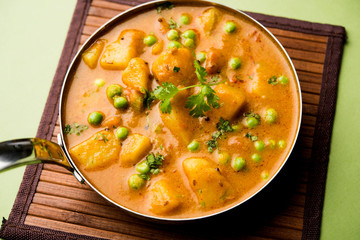 Indian Aloo Mutter curry - Potato and Peas immersed in an Onion Tomato Gravy and garnished with coriander leaves. Served in a Karahi/kadhai or pan or bowl. selective focus