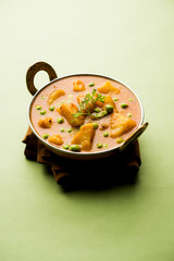 Indian Aloo Mutter curry - Potato and Peas immersed in an Onion Tomato Gravy and garnished with coriander leaves. Served in a Karahi/kadhai or pan or bowl. selective focus