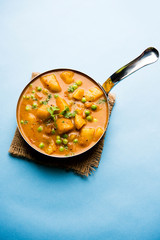 Indian Aloo Mutter curry - Potato and Peas immersed in an Onion Tomato Gravy and garnished with coriander leaves. Served in a Karahi/kadhai or pan or bowl. selective focus