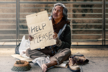poor homeless beggar siiting on pathway ask for help