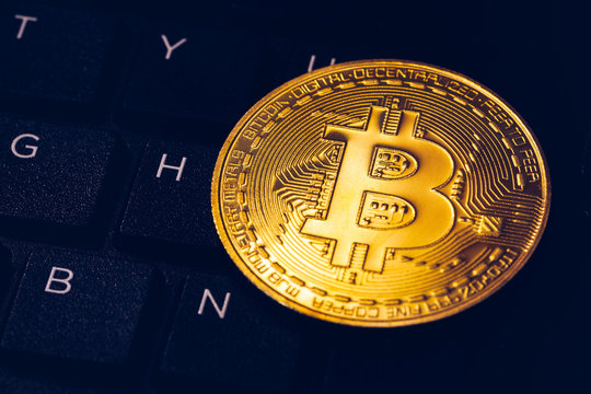 Bitcoin on compuer keyboard in background, symbol of electronic virtual money and mining cryptocurrency concept. Coin crypto currency bitcoin lies on the keyboard. Bitcoin on keyboard.