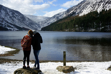 Two people on the shore of the mountain lake.Upper Lake.Glendalough.Wicklow Mountains.Ireland.