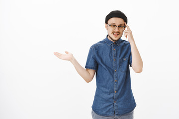 Man feeling irritated of stupid nonsense friend telling poking index finger at temple shrugging...