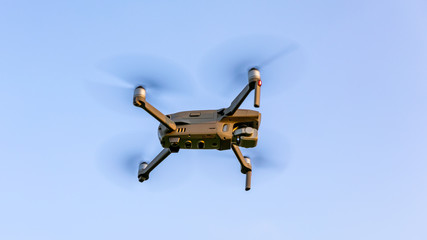 Drone flying over landscape. UAV drone copter flying with digital camera. Drone flying overhead in cloudy blue sky. Quad copter is flying over the  field.