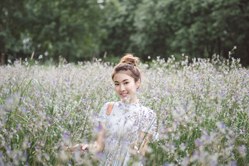 Woman with the white dress in the middle of the meadow with violet flowers Murdannia Giganteum in Prachinburi, Thailand. Photographer in nature. 