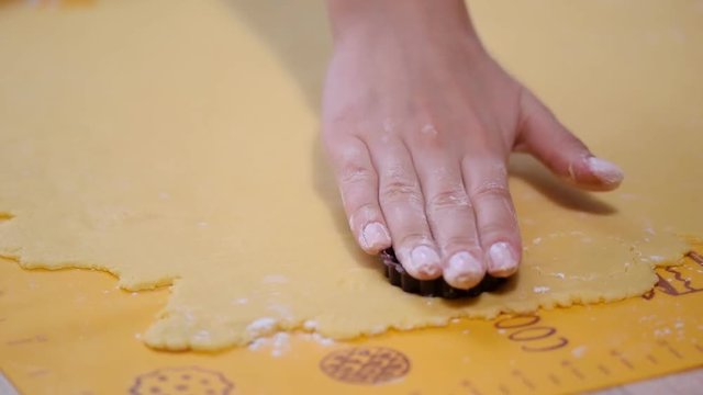 Cutting cookie shapes in rolled dough with cutter.