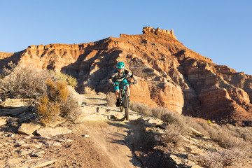 A woman rides a mountain bike over a small drop on the Jem trail below Gooseberry mesa in Southern Utah.