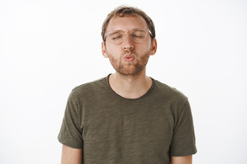 Fototapeta premium One kiss all it takes. Portrait of cute romantic and passionate european man with bristle in glasses closing eyes pulling head towards camera and folding lips in mwah making first step on date