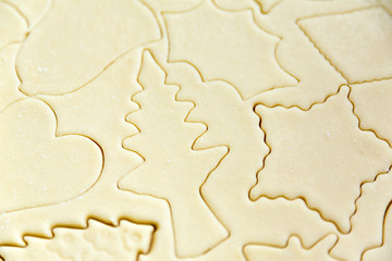 Homemade cookie dough shaped by cutters on a counter