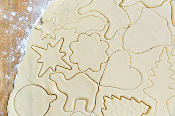 Homemade cookie dough shaped by cutters on a counter