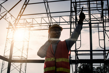 silhouette engineer holding radio and ordering at construction working site