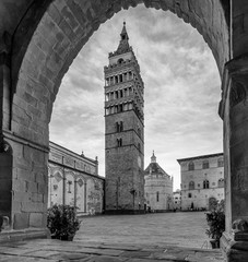 Black and white view of an almost deserted Piazza del Duomo framed by an arch of the Palazzo del Comune, Pistoia, Tuscany, Italy