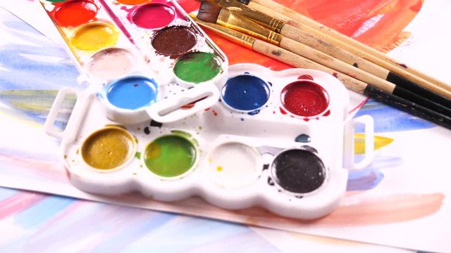Paint brushes and watercolor paints in motion on the table