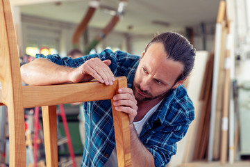 young worker in a carpenter's workshop with wooden chair