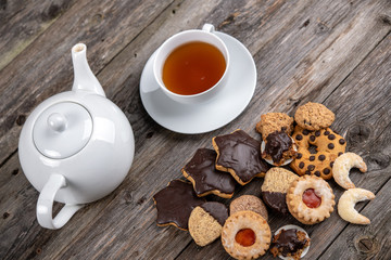 different homemade cookies with cup and pot of tea
