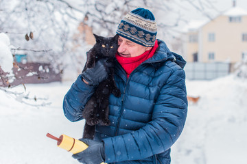 Concept of animals and pets. Best friend ever. Senior man with a black cat on a yard 