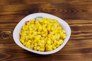Canned sweet corn in a bowl on wooden table