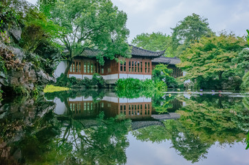Traditional Chinese house by pond with reflection in water, in a Chinese garden, near West Lake, Hangzhou, China
