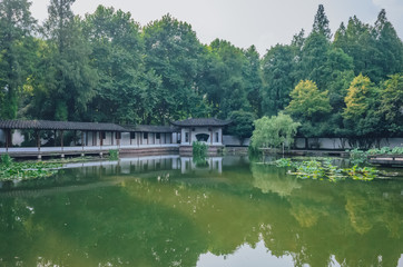 Obraz premium Traditional Chinese house by pond with reflection in water, in a Chinese garden, near West Lake, Hangzhou, China